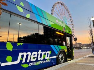A MetroBus with the Union Station Ferris Wheel in the background at dusk.